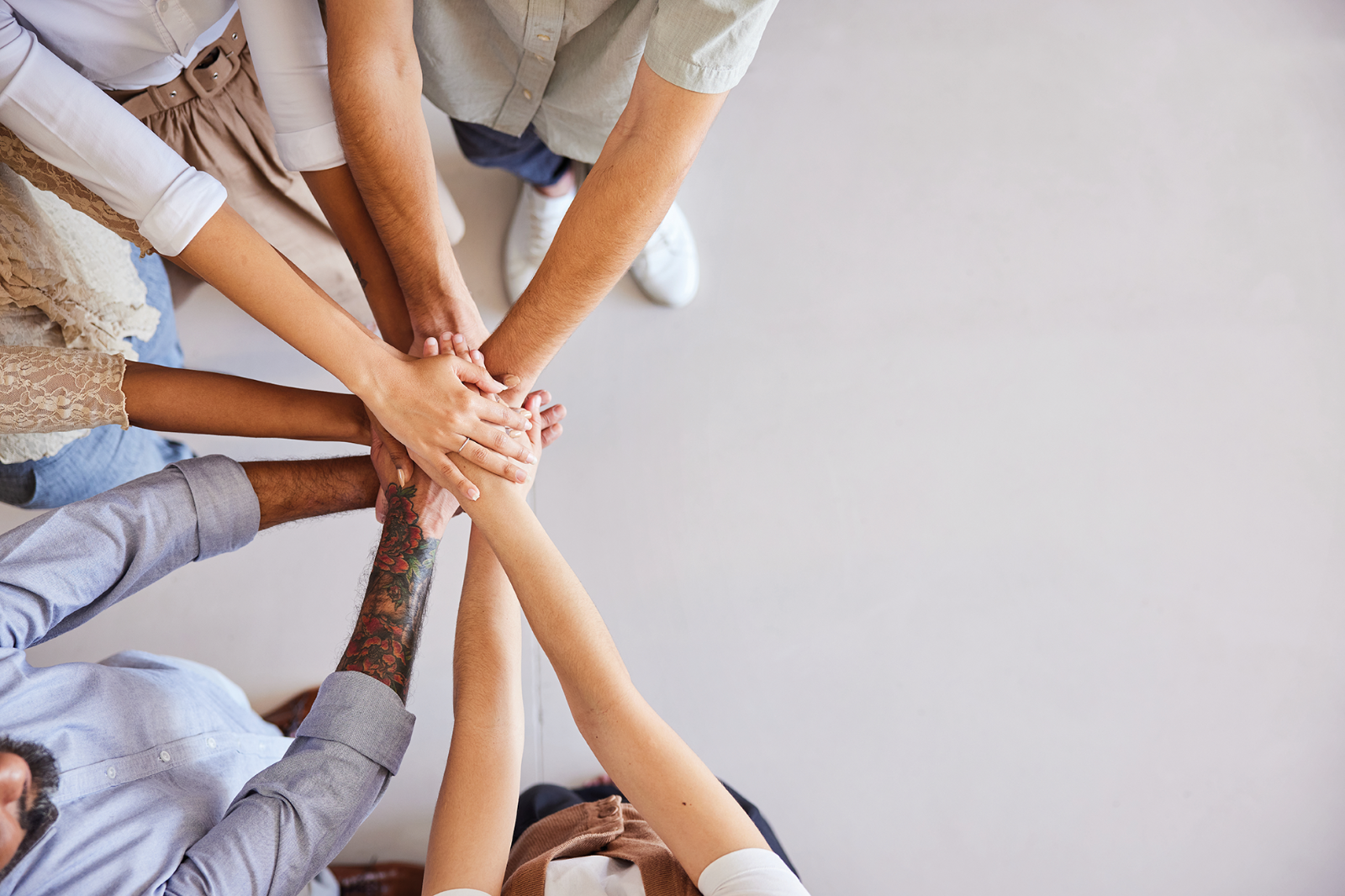 Mains d’un groupe divers empilées au centre pour symboliser l’unité et le travail d’équipe.